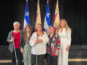 Martine Bédard, Pascale Dussault, et la conseillère municipale Mme Sandra El-Helou, devant les drapeaux du Québec et de la ville de Laval. 