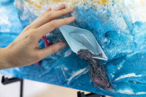 Photographie d'une main touchant une texture d'une oeuvre réalisée par une membre du RAAMM lors de l'atelier Peindre à l'oreille.