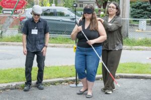 Photo de Sandrine Bastarache et Alain Renaud du RAAMM qui font parcourir une traversée sous bandeau à une candidate en utilisant le simulateur de feu sonore. Crédit photo : Réjean Poudrette